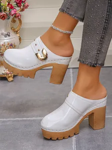 Side detail of white patent leather platform mules featuring gold horseshoe buckle deco