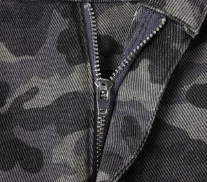 Macro view showing the silver metal zipper and texture of camouflage cargo jeans