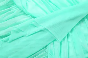 Detailed macro view of light mint green pleated mesh fabric texture for elegant dress