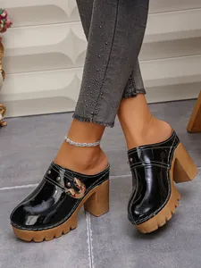 Close-up of elegant black patent leather platform mules with rivet and buckle details
