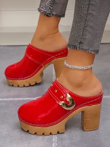 Close-up of red patent leather platform mules with gold buckle and rivet details.