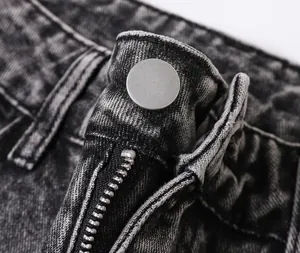 Close-up detail of retro washed denim jeans showing metal button and zipper fly