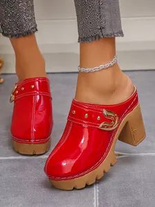 Red patent leather clogs with chunky heel and gold rivet details on wooden platform.