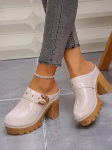 Stylish beige patent leather platform mules featuring gold buckle and studded details