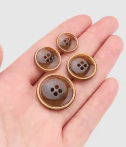 Close-up of premium brown marble texture urea buttons in four sizes held in hand