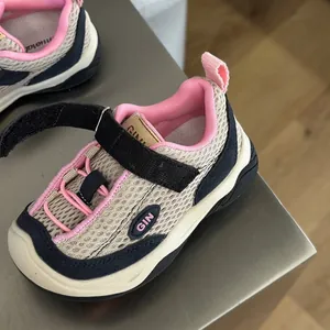 Primer plano de zapatillas de malla transpirable para niños con detalles rosa y velcro.