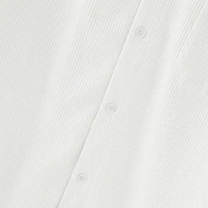 Detail van witte corduroy stoftextuur en knopen op een casual herenoverhemdjack