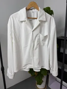 Detail van een wit herenoverhemd van corduroy met afhangende schouders en zakje