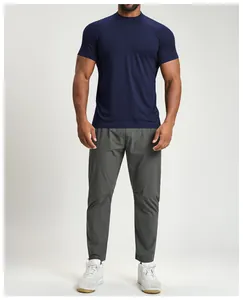 Full body view of a man in a navy blue breathable athletic t-shirt and grey pants