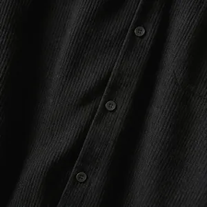 Detailopname van de zwarte corduroy stoftextuur en knopen op een herenoverhemdjack