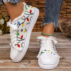 Detailed view of white canvas sneakers with festive Christmas light prints and frayed edges.