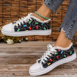 Close-up of women's black canvas shoes with colorful Christmas light print and frayed edges