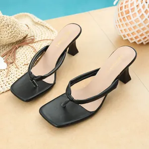 Close-up of black square toe thong sandals with architectural thin heels