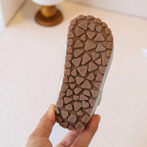 Close-up of the textured anti-slip brown rubber sole on toddler girl silver princess shoes.