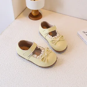 Close-up of cream yellow toddler Mary Janes with lace trim and bow detail