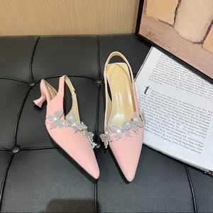 Detailed view of pink pointed-toe slingback heels with sparkling rhinestone butterflies