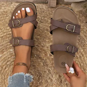 Detail of vintage brown women's flat sandals with double adjustable buckles and open-toe design.