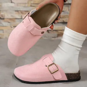 Detailed view of pink suede-like closed-toe clogs with metal buckle and cork-texture sole.