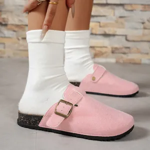 Close-up detail of pink suede-like closed-toe clogs with gold-tone adjustable buckle