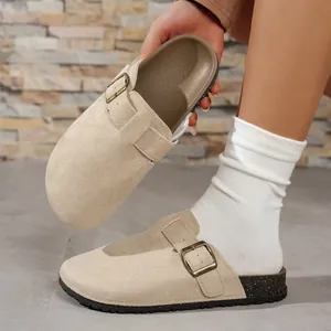 Detailed close-up of beige suede clog sandals featuring adjustable buckle and cork sole