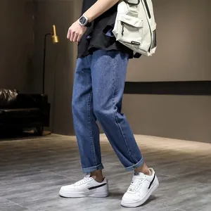 Detailweergave van blauwe slim fit stretch jeans voor heren met witte sneakers en rugzak