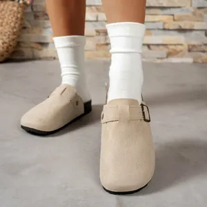 Close-up of beige suede closed-toe clog sandals worn with white socks for a cozy look.