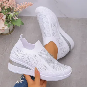 Nahaufnahme von weißen Keilsneakern mit funkelndem Strassbesatz aus Flyknit.
