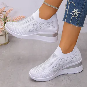 Detailansicht von weißen Strick-Sneakern mit glitzernden Strasssteinen und Keilsohle.