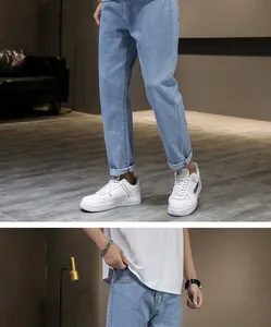 Detail van de lichtblauwe slim fit denim stof en de kortere zoom van deze heren jeans