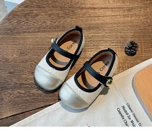 Close-up of stylish off-white girl's Mary Jane shoes with silver toe cap and black strap