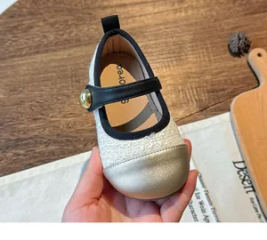 Close-up of girls tweed Mary Jane shoe with metallic gold toe cap and black strap