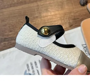 Close-up of girl's tweed princess shoe with gold toe cap and button
