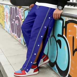 Detail van blauwe trainingsbroek met drukknopen aan de zijkant en reflecterende strip.