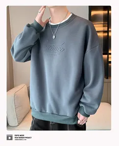 Gros plan d'un sweat gris avec motif en relief sur la poitrine et poignets verts