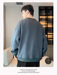 Détail de la vue arrière d'un sweat-shirt à col rond bleu-gris ample pour hommes en intérieur.
