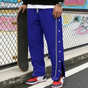 Detail van blauwe sportbroek met drukknopen aan de zijkant en reflecterende strip.