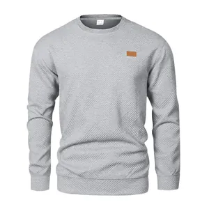 Detail eines grauen Herren-Sweatshirts mit strukturiertem Stoff und Leder-Patch-Akzent.