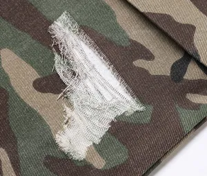 Detailed close-up showing the distressed ripped effect on camouflage cargo pants fabric