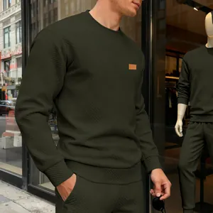 Detailansicht des strukturierten Stoffes und Brust-Patches eines olivgrünen Herren-Sweatshirts.