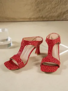Primo piano di eleganti sabot rossi a tacco alto da donna con trama a coccodrillo.