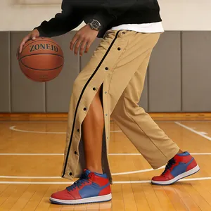 Detailopname van een kaki heren sportbroek met drukknopen aan de zijkant op een sportveld