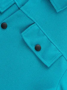Détail en gros plan d'une veste en maille gaufre turquoise avec rabat de poche et bouton