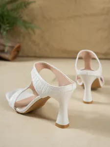 Dettaglio delle scarpe bianche con goffratura coccodrillo ed eleganti tacchi a spillo
