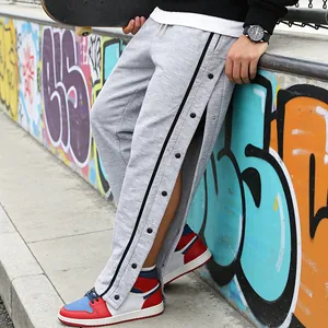 Detailopname van grijze joggingbroek met drukknopen aan de zijkant en zwarte strepen