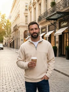 Μοντέλο που φοράει μπεζ φλις φούτερ με μισό φερμουάρ σε ένα αστικό εξωτερικό περιβάλλον
