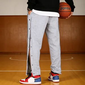 Grijze heren trainingsbroek met drukknopen, losse pasvorm op een echt basketbalveld