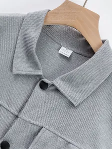 Gros plan d'un col de veste gris gaufré avec des boutons noirs et une étiquette d'entretien