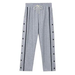 Detail van grijze tear-away broek met zwarte zijstrepen en functionele drukknoppen.