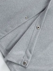 Gros plan d'une veste de travail grise en maille gaufrée avec boutons-pression.