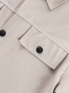 Détail de la texture gaufre et du bouton noir sur une veste de travail décontractée.